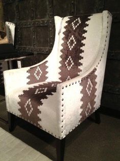 a white and brown chair sitting on top of a floor next to a black wall