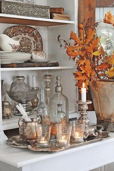 a white table topped with lots of glass vases filled with flowers and candles sitting on top of it