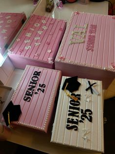 four pink graduation cakes with white frosting and black writing on them are sitting on a table