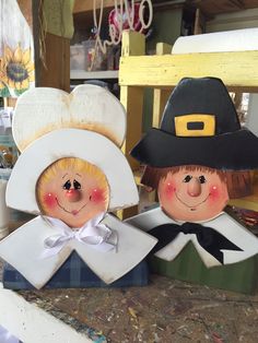 two little scarecrows sitting next to each other on top of a wooden table