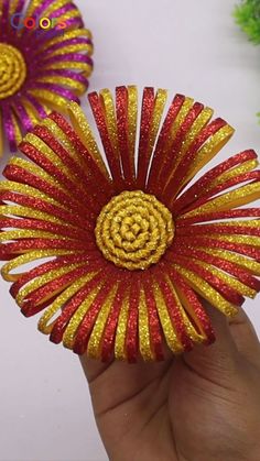 two red and yellow flowers are being held in someone's hand with gold glitters