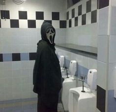 a person wearing a mask standing in front of urinals