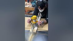 a man working on a piece of wood with a driller and visor in his hand