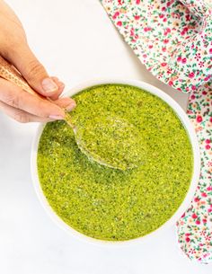 a person dipping pesto into a white bowl