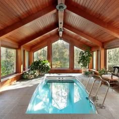 an indoor swimming pool in the middle of a room with large windows and wood paneling