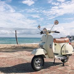 a scooter is parked on the brick road by the beach