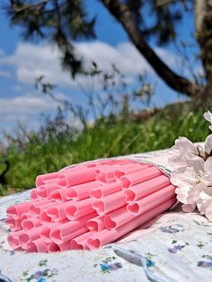 a bunch of pink straws sitting on top of a table next to some flowers