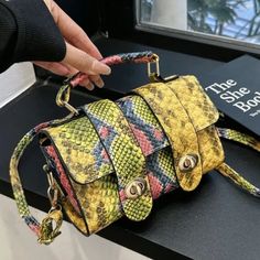 a handbag is being held up by someone's hand on top of a table