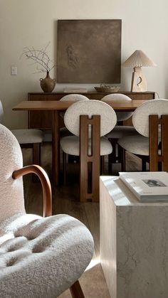 a dining room table with chairs and a painting on the wall