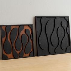 two black and brown art pieces sitting on top of a wooden table