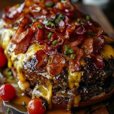 a close up of a plate of food with meat and cheese on it, topped with tomatoes