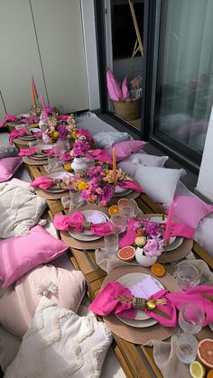 a long table is set up with pink napkins and plates on it for a party