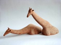 a clay giraffe laying on its side with it's legs spread out