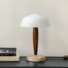 a table lamp sitting on top of a black desk next to books and a phone