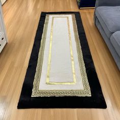 a black and white rug with gold trim on the floor in a living room next to a couch