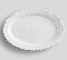 an empty white plate with beading on the rim and bottom, against a gray background