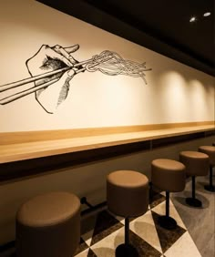 a restaurant with several stools in front of the wall and an artistic drawing on the wall