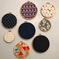 six embroidery hoops with different designs on them hanging on a wall in a room