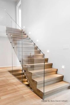 an empty staircase with glass railing and wooden steps