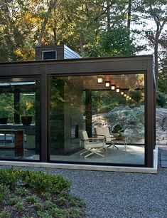 an outdoor room with glass walls and sliding doors on the outside, surrounded by trees