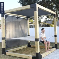 a man sitting on top of a bed frame in the grass next to a fence