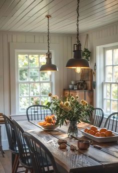 a wooden table topped with lots of fruit next to two lights hanging from the ceiling