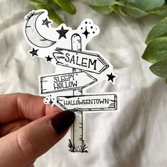 a hand holding a sticker that says salem, sleepy hollow and halloween town on it