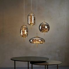 three lights hanging from the ceiling above a table with two tables in front of it