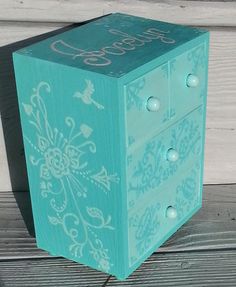 a blue wooden box with white designs on it