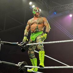 a wrestler standing on top of a rope in the middle of a wrestling ring with his arms and legs wrapped around him