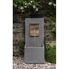 a water fountain in front of a stone wall