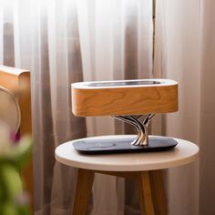 a table with a phone on top of it next to a flower pot and window