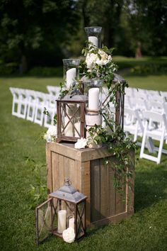 an arrangement of candles and flowers on top of a wooden crate at a wedding ceremony