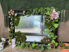 a mirror sitting on top of a table covered in plants