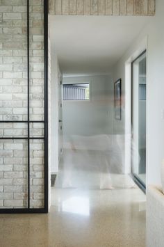 a blurry photo of a person walking down a hall way in a white room