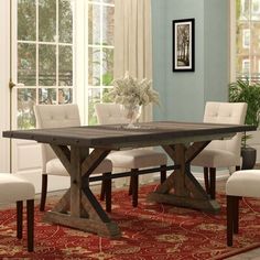 a dining room table with white chairs and a red rug in front of the window