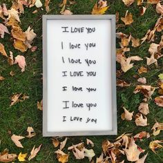 a sign that says i love you in the grass with leaves around it and on the ground