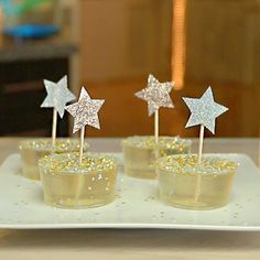 small cupcakes with glitter stars on them are sitting on a white platter