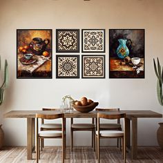 a dining room table with four paintings on the wall above it and two vases