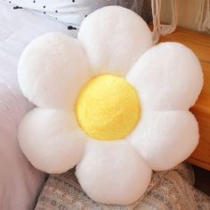 a white flower pillow sitting on top of a bed