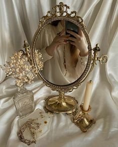 a woman taking a selfie in front of a mirror with jewelry and candles on it