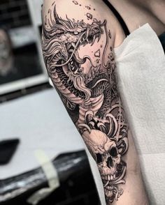 a man with a dragon and skull tattoo on his arm