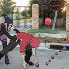 two people are playing with some cupcakes on the street in front of a fence