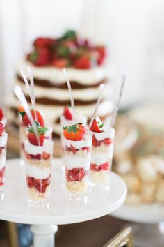 small desserts with strawberries and whipped cream are on a cake stand, ready to be served