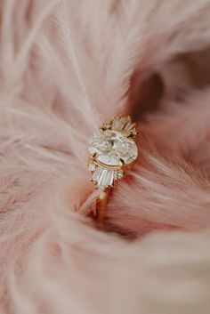 a close up of a feather with a ring in it's center and some diamonds on the side