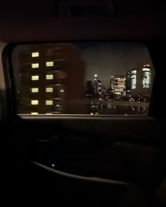 the view from inside a car at night with city lights in the distance and skyscrapers lit up