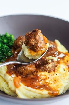 a bowl filled with meatballs and gravy next to broccoli