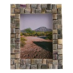 a stone frame with a dirt road and mountains in the background