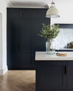 a kitchen with black cabinets and white counter tops, an island in front of it