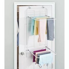 an over the door drying rack holds folded towels and other items in front of a white door